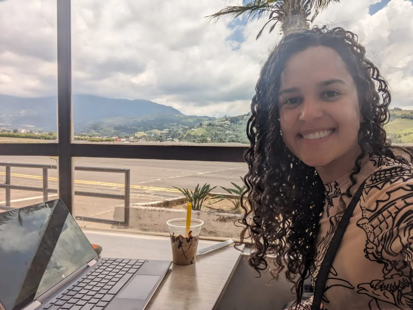 Jenifer working on her laptop with Colombian mountains in the background