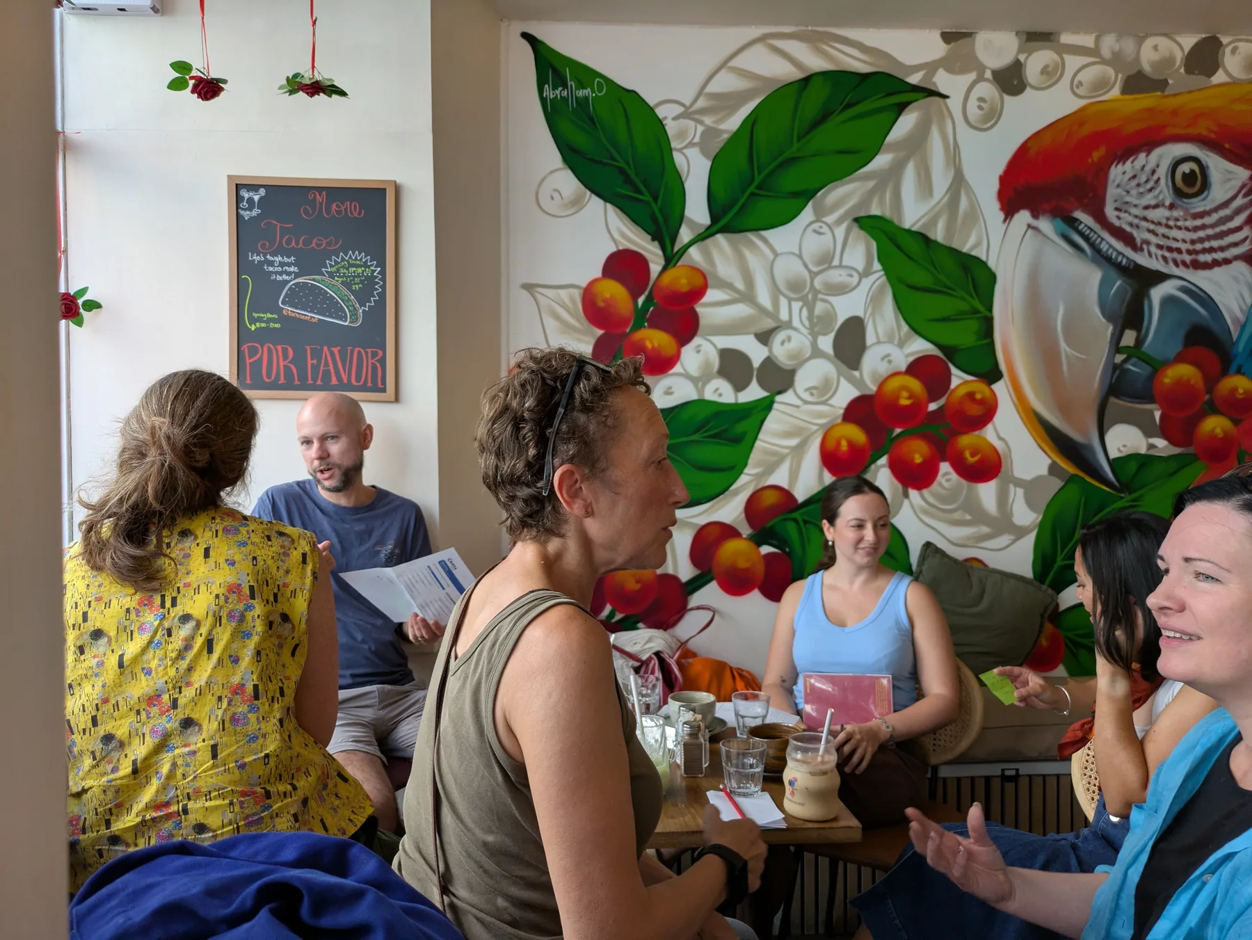 A small group chatting beside a colourful café mural