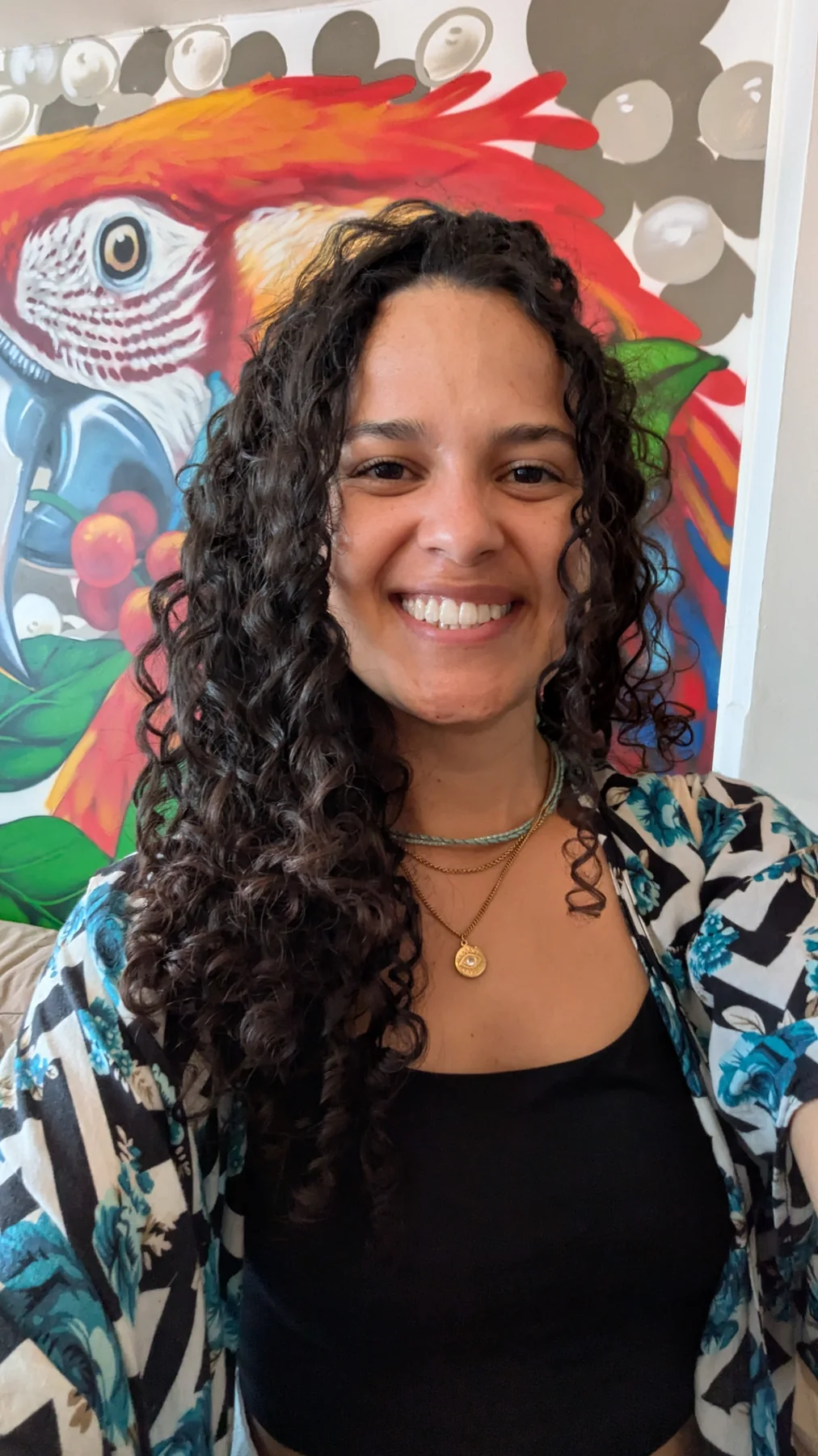 Jenifer smiling in front of a colourful café mural
