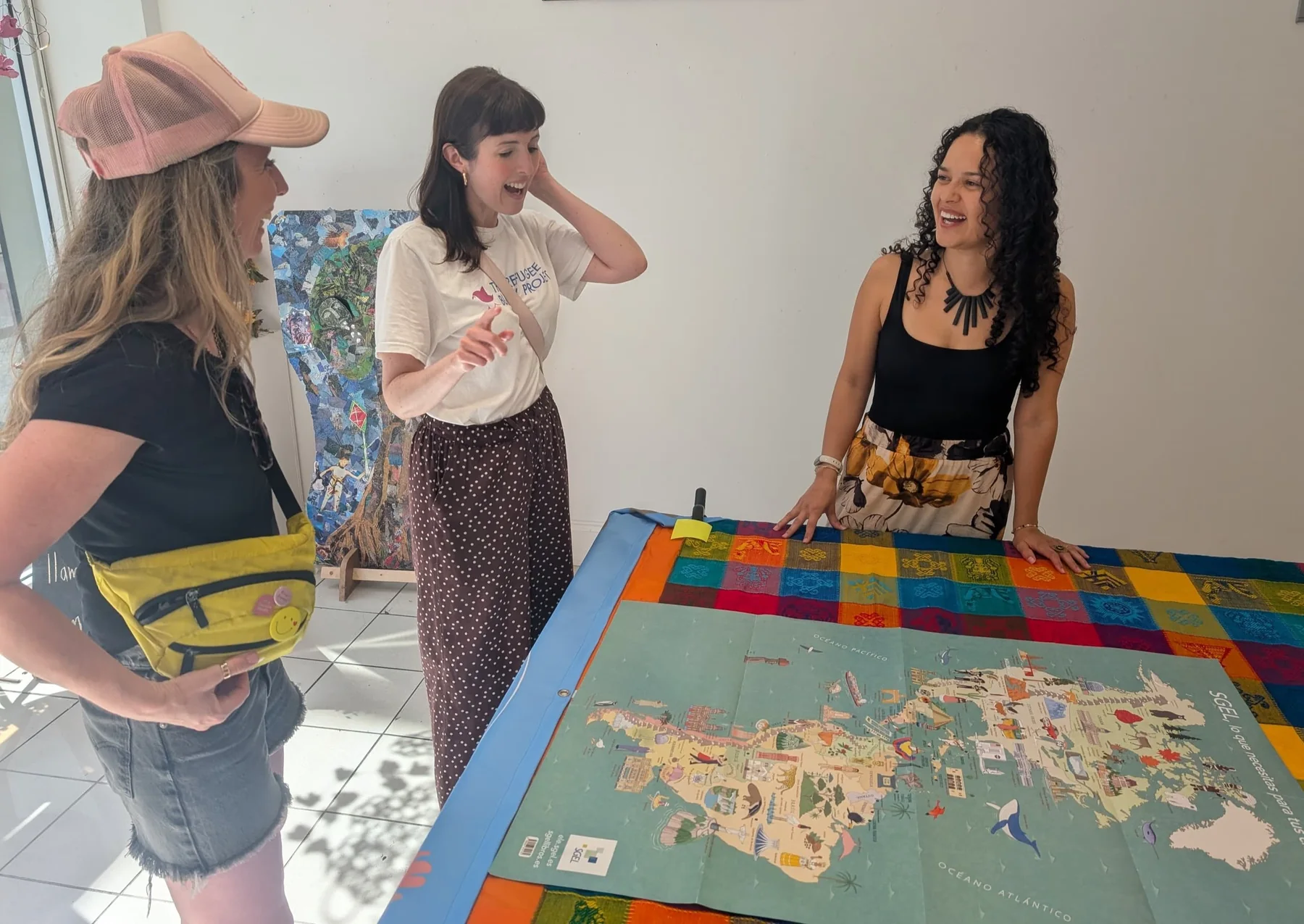 Three people smiling and talking around a colourful map activity
